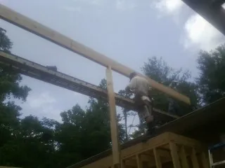 Carpenter setting a ridge beam over a new addition frame — Ice Dam Removal by Roofing Brothers in Bulger