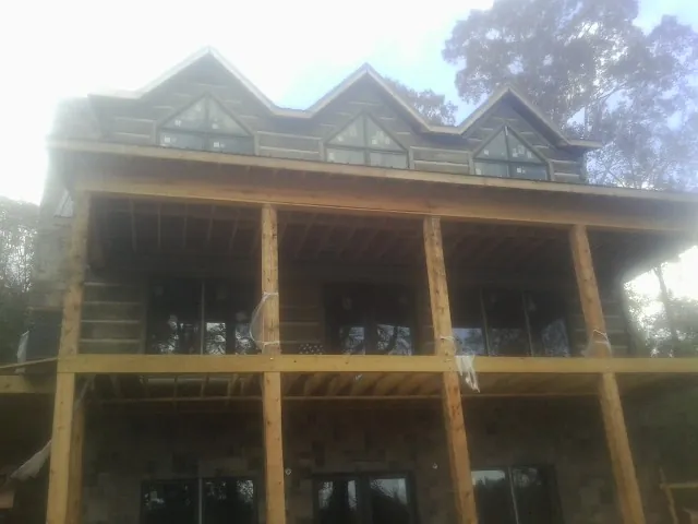 Dormers and porch framing on a large log home under construction — Roof Coating work by our crew in Bulger