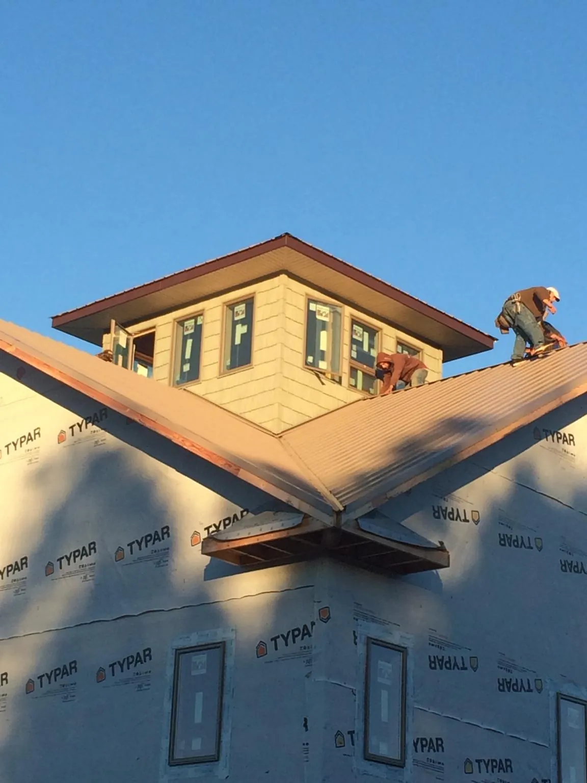 Roofers working around a rooftop cupola on a new metal roof at sunset — Roof Waterproofing in Bulger by Roofing Brothers